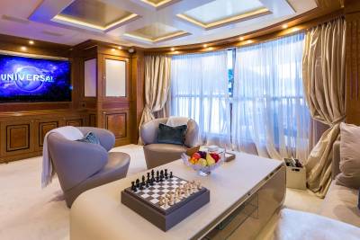 Luxurious yacht interiors offer a sophisticated entertainment space with a large screen, plush seating, and a chess set for leisurely evenings.