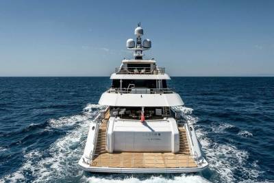 A luxurious white yacht glides through the deep blue ocean under a clear sky.
