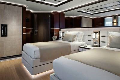 Luxurious twin beds are perfectly appointed in this elegant stateroom with rich wood accents and ambient lighting.