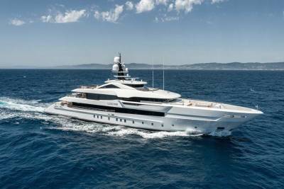 The luxurious yacht LUSINE glides through the deep blue ocean under a bright, cloudy sky.