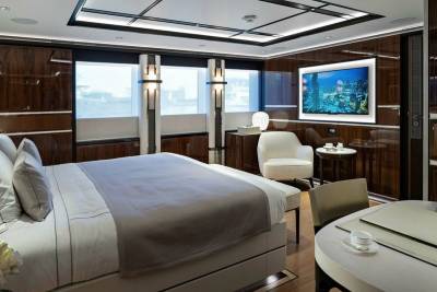 Luxurious yacht accommodations offer a serene retreat with a city skyline view on the television.