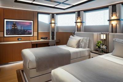 Luxurious twin beds await in this elegantly appointed cabin, featuring a stunning city skyline on screen and ambient wall lighting.