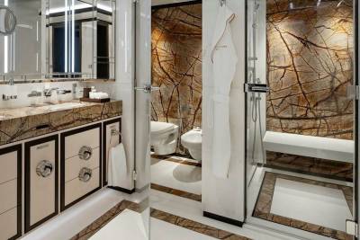 Luxurious bathroom featuring a marble vanity, a separate toilet and bidet, and a spacious walk-in shower with a natural stone accent wall.