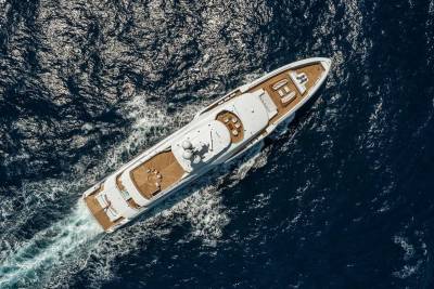A luxurious white yacht glides through the deep blue ocean, leaving a trail of white foam in its wake.