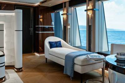 Relax on a plush chaise lounge with a stunning ocean view from this luxurious yacht cabin.