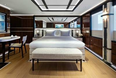 Luxurious yacht accommodations feature a plush king-sized bed, elegant mirrored headboard, and rich wood paneling.