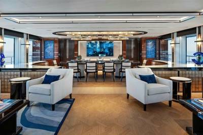 Luxurious yacht interiors feature a sophisticated dining area with a large screen and elegant seating.