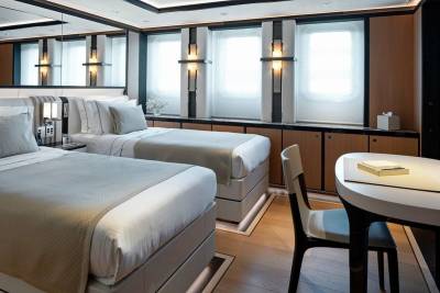 Luxurious twin beds are neatly made in this elegantly appointed cabin, ready for a restful night's sleep.