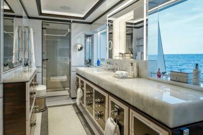 Luxurious yacht bathroom features a marble vanity, glass shower, and ocean views.