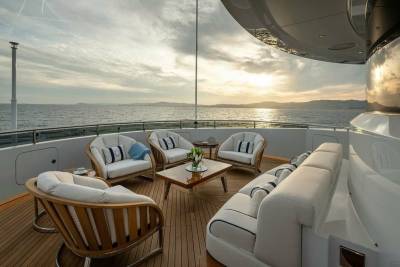 Luxurious outdoor seating on a yacht deck offers a serene setting for enjoying a tranquil sunset over the ocean.