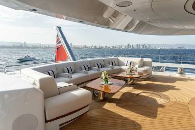 Luxurious white sofas and polished wooden decks create a stunning outdoor lounge area with a city skyline in the distance.