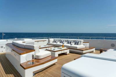 Luxurious white sofas and sleek wooden accents create an inviting outdoor lounge space on this elegant yacht.