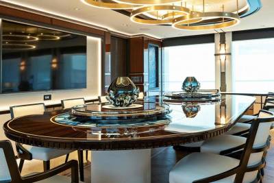 A luxurious dining room features a polished wood table with ornate vases and elegant chairs, illuminated by a modern chandelier.