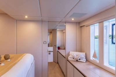 A serene cabin aboard a yacht offers a cozy retreat with a comfortable bed, ample storage, and large windows overlooking the tranquil sea.