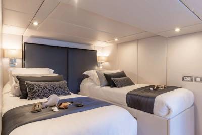 Twin beds with elegant grey accents and decorative seashells offer a serene retreat in this luxurious cabin.