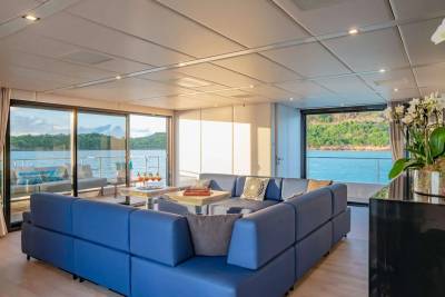 Luxurious blue sectional seating offers a prime view of the tranquil turquoise waters from this elegant yacht salon.