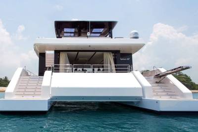 A sleek catamaran yacht with elegant stairs awaits exploration on tranquil turquoise waters.