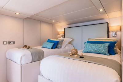 Luxurious twin beds are adorned with plush blue and patterned pillows, creating a serene and inviting retreat.