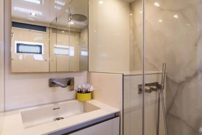 A modern bathroom features a sleek sink, minimalist cabinetry, and a glass-enclosed shower with a rainfall showerhead.