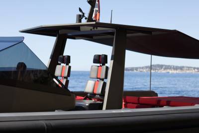 Luxurious red and grey seats offer a comfortable perch on this sleek modern boat, with a picturesque coastline in the background.