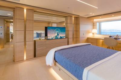 Luxurious yacht accommodations offer a serene bedroom with a large window overlooking the sea and a modern entertainment system.