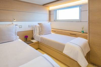 Twin beds with crisp white linens are neatly made in this serene cabin, bathed in soft, warm light.