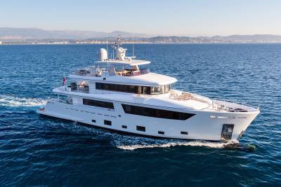 A sleek white superyacht glides through the deep blue Mediterranean Sea under a clear sky.