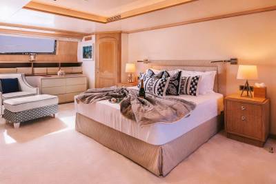 Luxurious yacht stateroom features a plush king-sized bed, elegant seating, and a private balcony with ocean views.