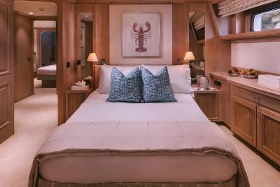The master stateroom offers a luxurious retreat with its plush bedding, intricate wood detailing, and charming lobster artwork.