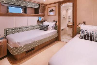 Twin beds with patterned upholstery and a porthole window create a cozy cabin atmosphere.