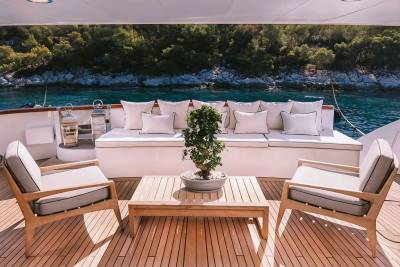 Relax on the deck of a luxurious yacht surrounded by the stunning turquoise waters and lush green coastline.