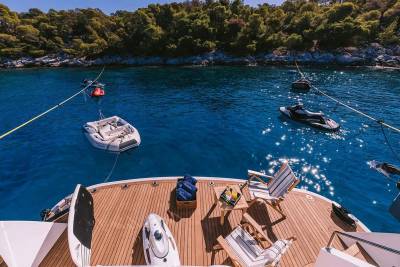 Relax on the deck of a luxury yacht surrounded by crystal-clear blue waters and lush green hills.