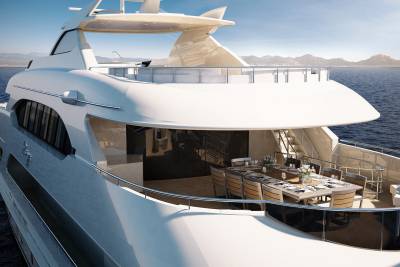 An elegant yacht with a spacious outdoor dining area cruises on a calm, blue sea under a clear sky.