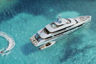 A luxurious yacht glides through crystal-clear turquoise waters, accompanied by jet skis and a tender.