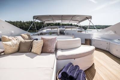 Luxurious cushions and plush towels adorn the deck of a sleek yacht, inviting relaxation amidst a serene waterscape.