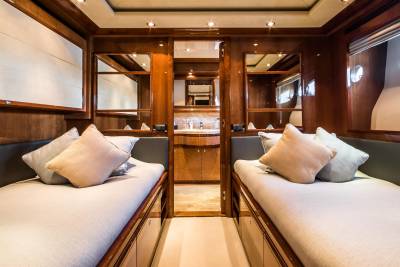 Luxurious twin beds with plush pillows are bathed in warm light within this elegantly appointed yacht cabin.