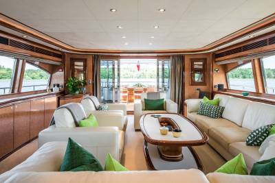 Luxurious yacht interiors feature plush white sofas adorned with vibrant green pillows, offering a serene retreat with scenic water views.