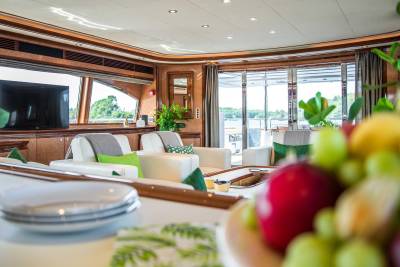 Luxurious yacht interior offers a serene lounge area with plush seating and stunning water views through expansive windows.