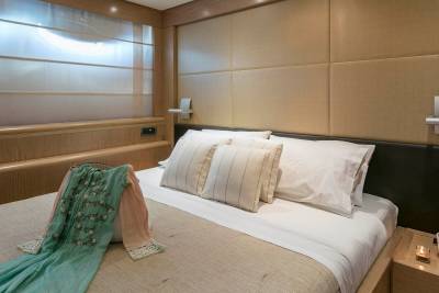 A luxurious yacht cabin offers a serene retreat with plush bedding, elegant wood finishes, and a touch of personal style.