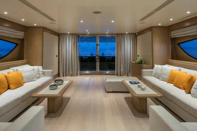 Luxurious yacht salon offers a serene evening view of the sea through panoramic windows.