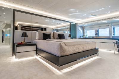 Luxurious yacht stateroom features a plush king-sized bed, mirrored walls, and ambient lighting for ultimate relaxation.