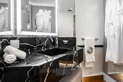 Luxurious white bathrobes hang in a modern bathroom with a sleek black marble vanity and sink.