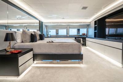 Luxurious yacht bedroom features a plush bed, mirrored walls, and a stunning ocean view through panoramic windows.