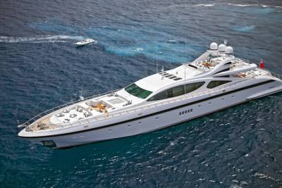 A sleek white superyacht glides through the deep blue ocean, leaving a wake behind it.