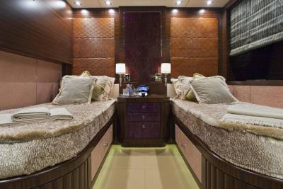 Luxurious twin beds with plush bedding and elegant wooden accents create a serene sleeping space on this yacht.
