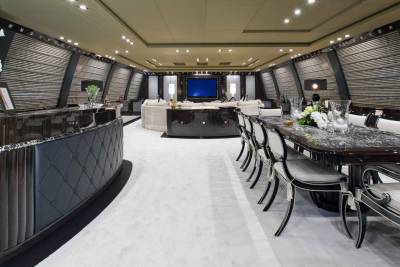 Luxurious yacht interiors feature a sleek bar, elegant dining area, and a spacious lounge with a large screen television.