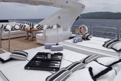 Luxurious yacht deck seating with a backgammon board and drinks invites relaxation on the open water.