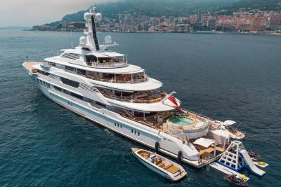 A luxurious superyacht anchors in the azure waters off a picturesque coastal city.