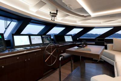 The modern yacht bridge offers panoramic views through expansive windows, showcasing a sophisticated navigation system and luxurious seating area.