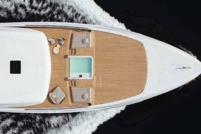 A luxurious white yacht glides through dark water, its wooden deck featuring a tranquil pool and comfortable seating areas.